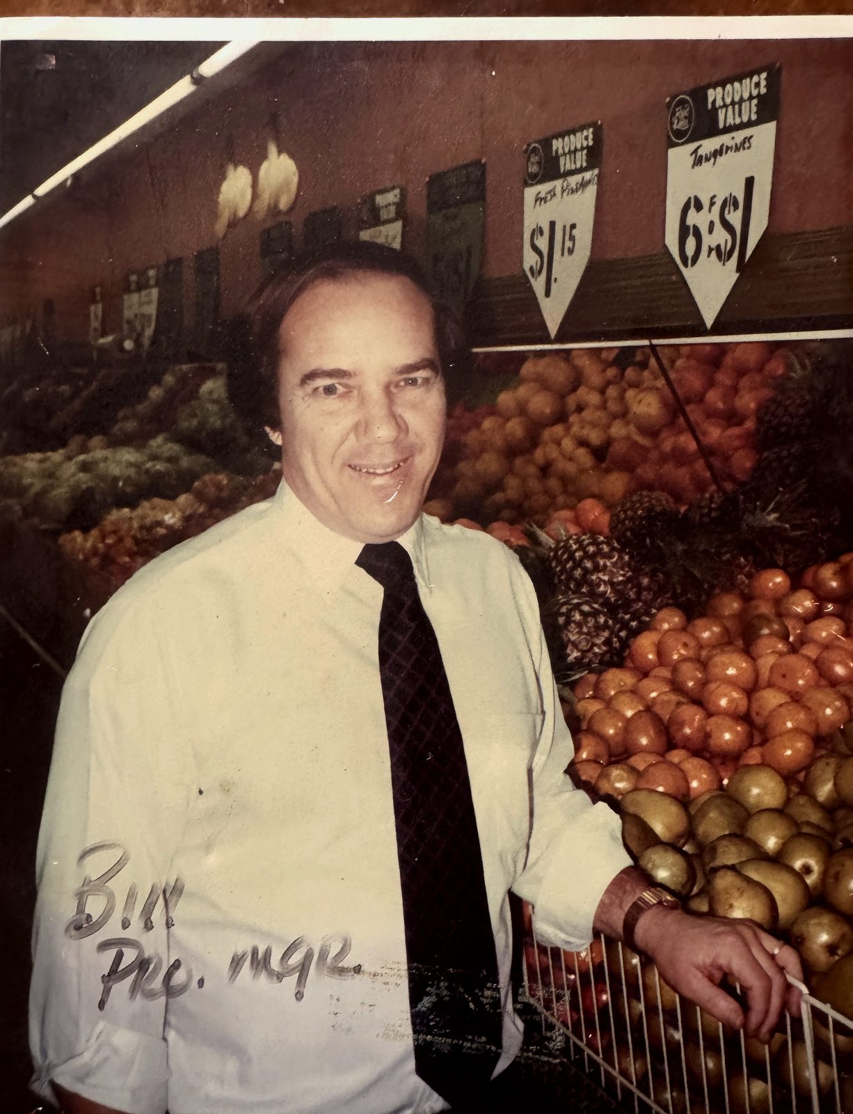 Bill with fresh produce and signs at The Farm Connection stand