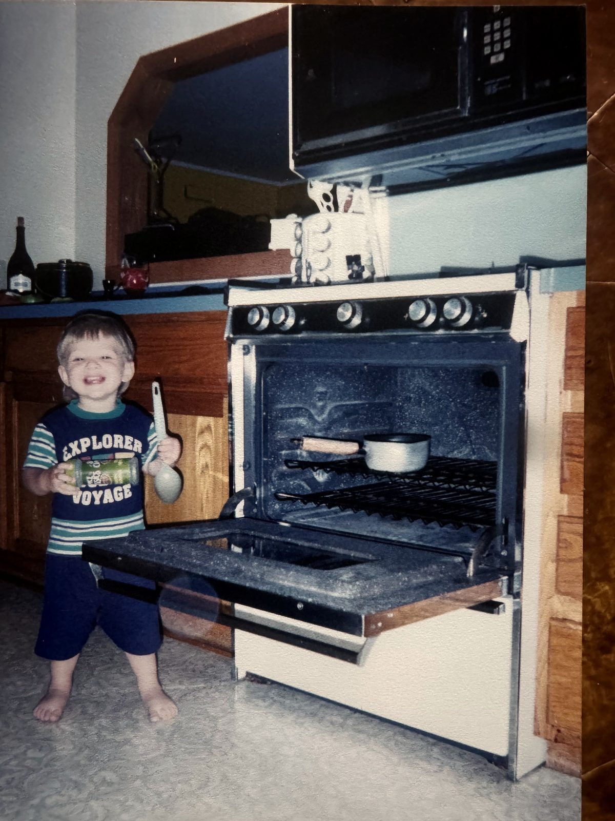 Young Cade in the kitchen with a spoon near the oven